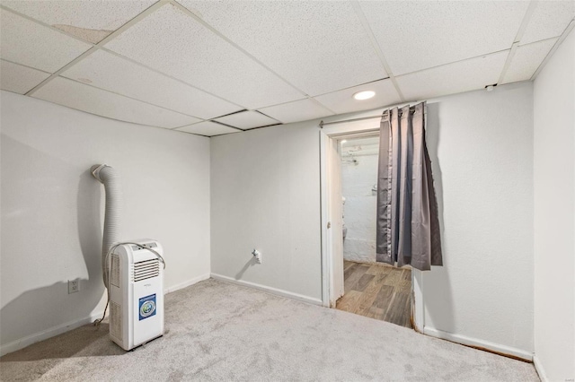 finished below grade area featuring carpet flooring, a paneled ceiling, and baseboards