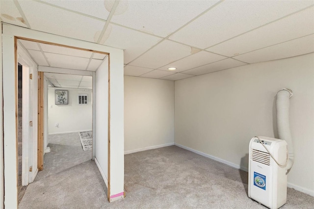 finished below grade area featuring a paneled ceiling, baseboards, and carpet