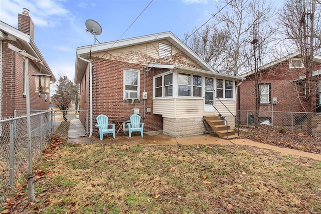 rear view of house with a sunroom, brick siding, a fenced backyard, and entry steps