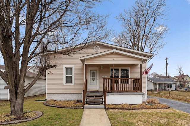 bungalow-style house with aphalt driveway, a front lawn, and a porch