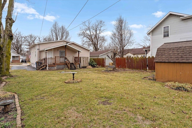 view of yard featuring a shed, an outdoor structure, fence, and a wooden deck