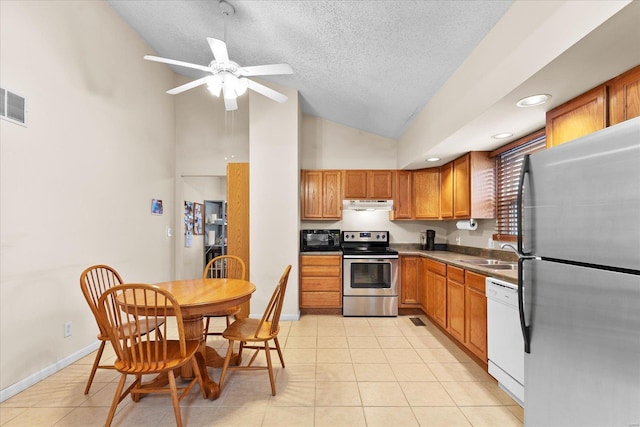 kitchen with light tile patterned floors, stainless steel appliances, brown cabinetry, a sink, and under cabinet range hood