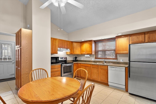 kitchen with under cabinet range hood, appliances with stainless steel finishes, a sink, and light tile patterned flooring