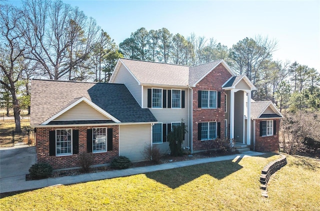 view of front of house with brick siding, a shingled roof, and a front yard