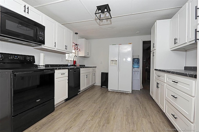 kitchen with dark countertops, a sink, light wood-style flooring, and black appliances