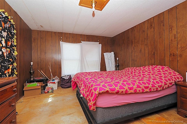 bedroom featuring concrete flooring and wooden walls