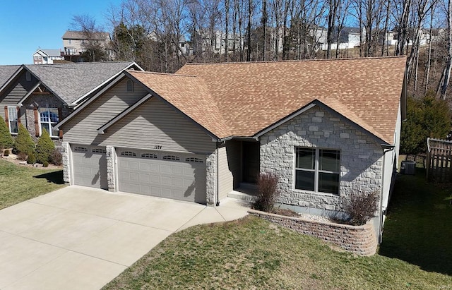 view of front of property with a shingled roof, an attached garage, central AC, driveway, and a front lawn