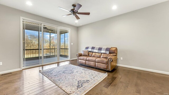 living room featuring visible vents, baseboards, wood finished floors, and a ceiling fan