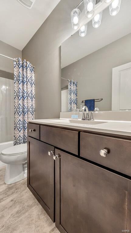 bathroom featuring shower / bath combination with curtain, toilet, vanity, and vaulted ceiling