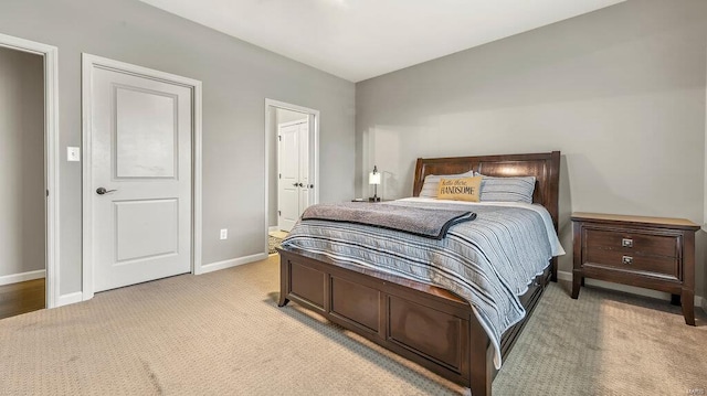 carpeted bedroom featuring baseboards and connected bathroom