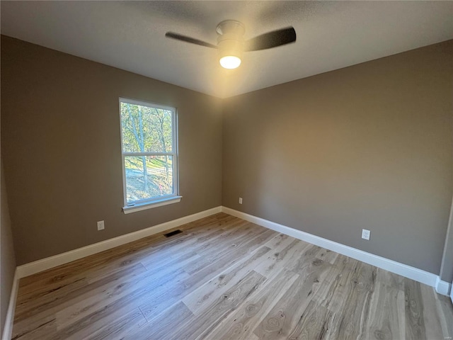 spare room featuring light wood-style floors, visible vents, ceiling fan, and baseboards