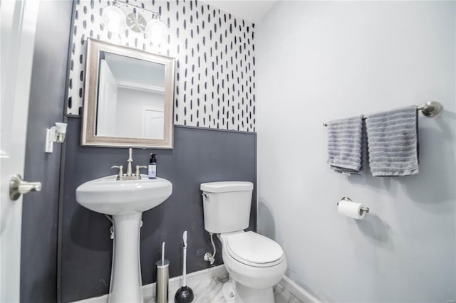 bathroom with marble finish floor, baseboards, and toilet