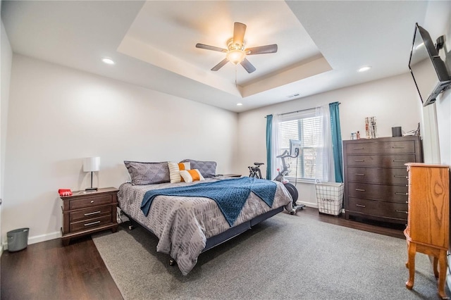 bedroom featuring dark wood-style flooring, recessed lighting, a raised ceiling, ceiling fan, and baseboards