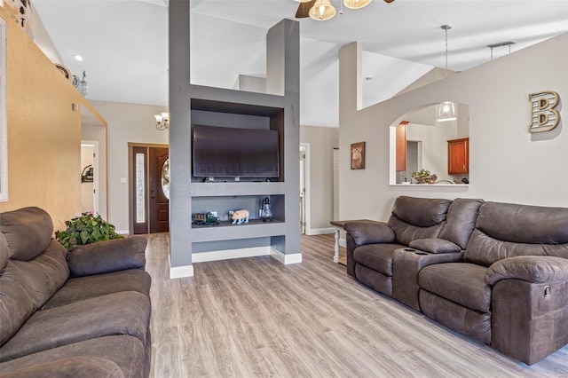 living area with light wood finished floors, high vaulted ceiling, and baseboards