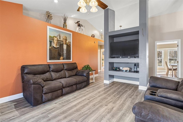 living area featuring built in shelves, baseboards, lofted ceiling, and wood finished floors