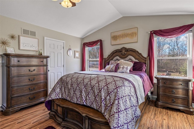 bedroom with light wood-type flooring, visible vents, multiple windows, and lofted ceiling