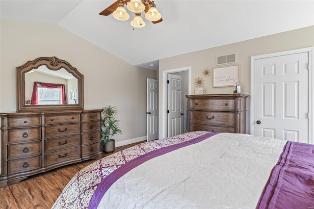 bedroom featuring visible vents, dark wood-type flooring, a ceiling fan, baseboards, and vaulted ceiling