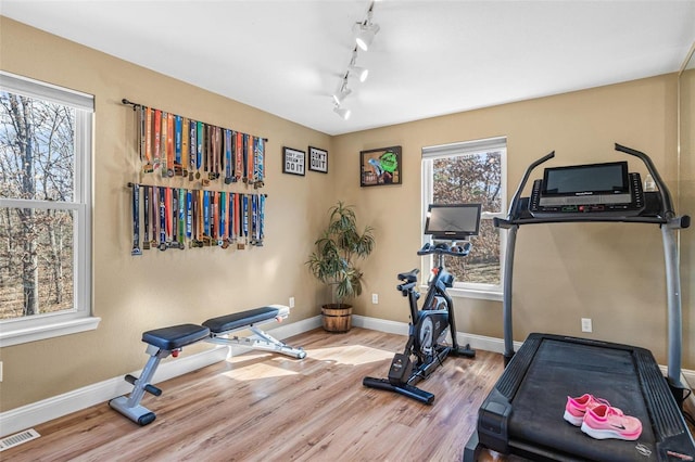 workout room with visible vents, baseboards, wood finished floors, and rail lighting