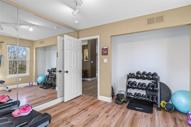 exercise room with visible vents, baseboards, and light wood-style floors