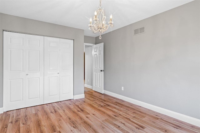 unfurnished bedroom with visible vents, a closet, light wood-style floors, baseboards, and a chandelier