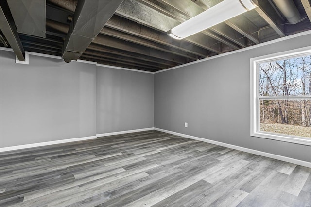 below grade area featuring a healthy amount of sunlight, baseboards, and wood finished floors