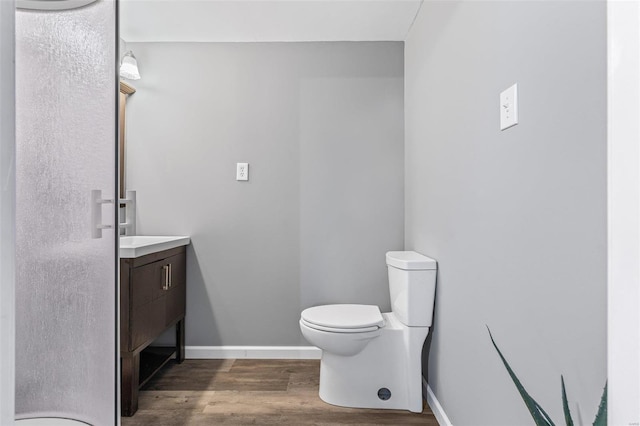 bathroom with baseboards, toilet, wood finished floors, and vanity