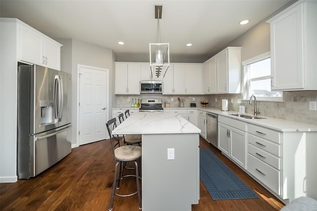 kitchen with a sink, white cabinets, a kitchen island, and stainless steel appliances