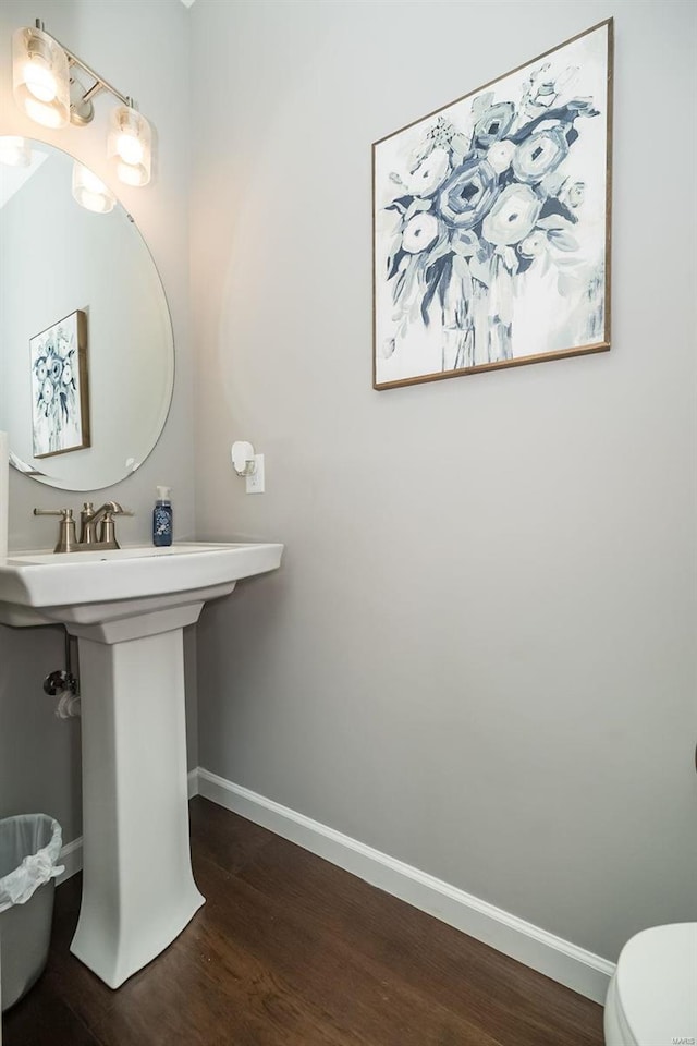 half bathroom with toilet, wood finished floors, and baseboards