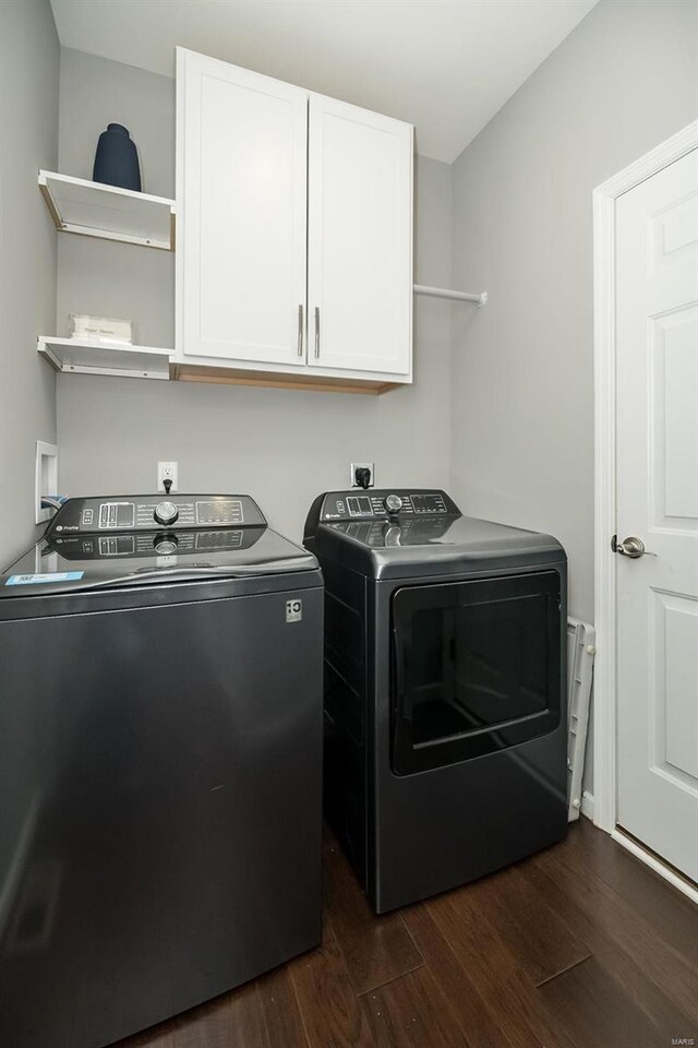 clothes washing area with dark wood finished floors, separate washer and dryer, and cabinet space