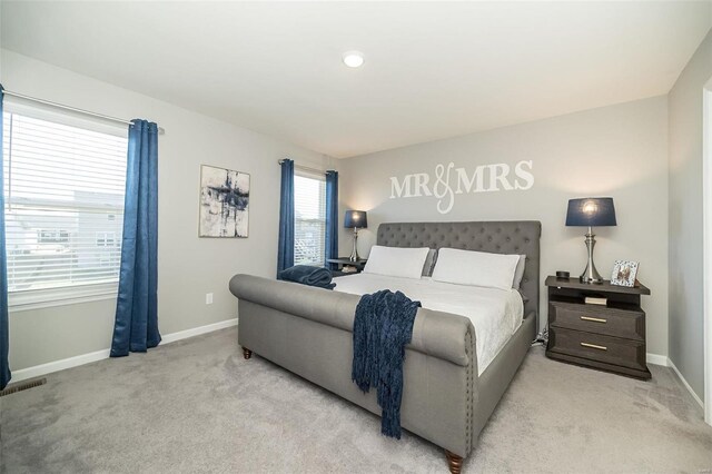 bedroom with light carpet, visible vents, and baseboards