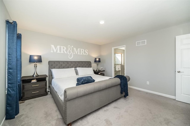 bedroom with visible vents, light colored carpet, ensuite bathroom, and baseboards