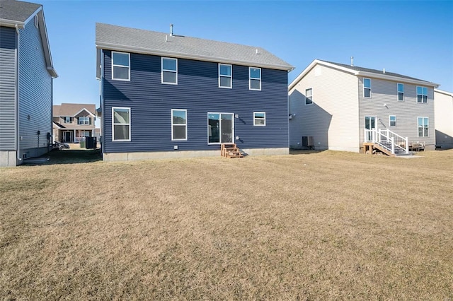 rear view of property featuring central air condition unit, entry steps, and a yard