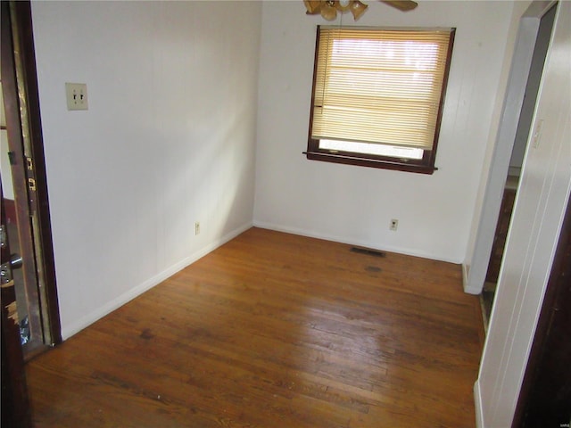 spare room with a ceiling fan, visible vents, baseboards, and wood finished floors