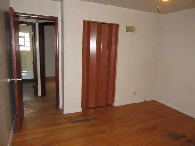 unfurnished bedroom featuring wood finished floors and visible vents