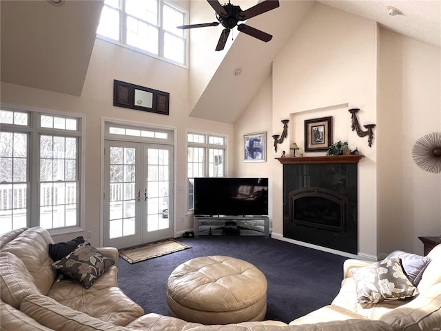 carpeted living area with french doors, a fireplace, a towering ceiling, and a healthy amount of sunlight