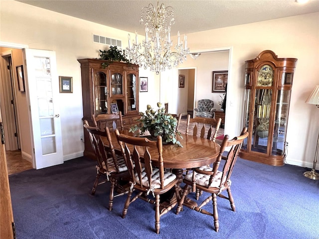 carpeted dining room with an inviting chandelier, baseboards, visible vents, and a textured ceiling