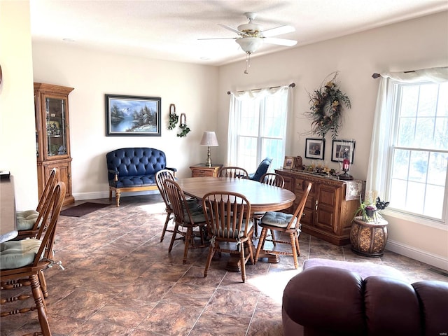 dining space with ceiling fan and baseboards