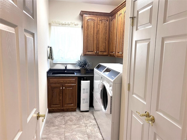 clothes washing area featuring washing machine and dryer, a sink, and cabinet space