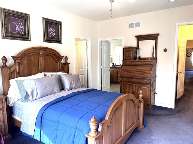 bedroom featuring connected bathroom, visible vents, dark carpet, and baseboards