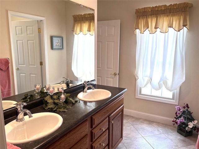 full bath with double vanity, baseboards, a sink, and tile patterned floors