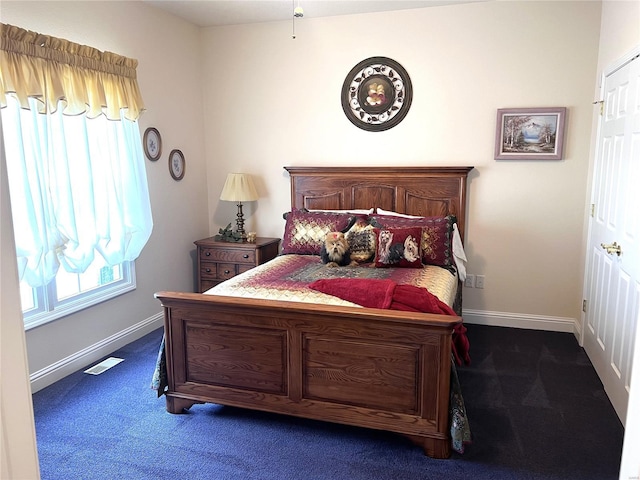 carpeted bedroom with visible vents, baseboards, and multiple windows