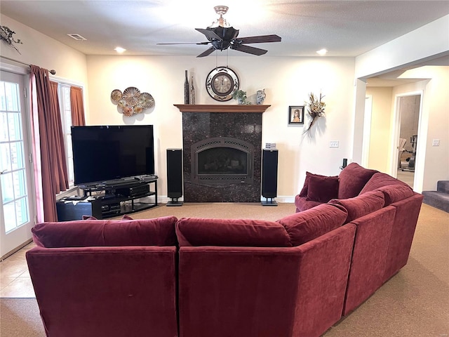 carpeted living room featuring a tile fireplace, visible vents, ceiling fan, and baseboards