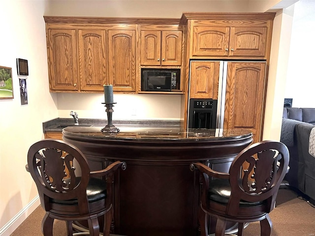 kitchen with dark countertops, black microwave, a sink, and a kitchen bar