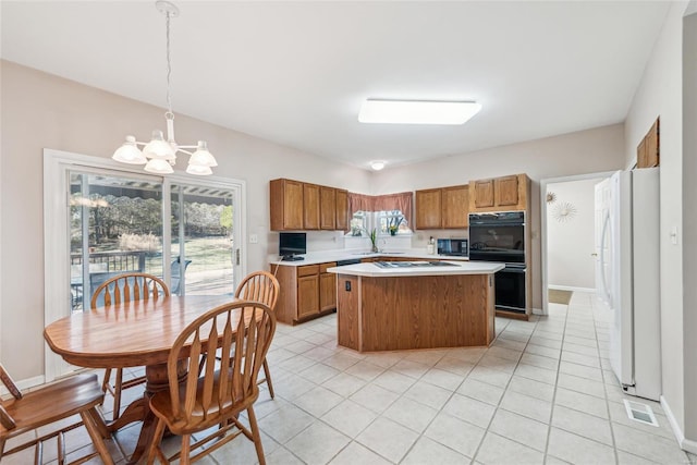 kitchen featuring brown cabinetry, a kitchen island, a sink, black appliances, and light countertops