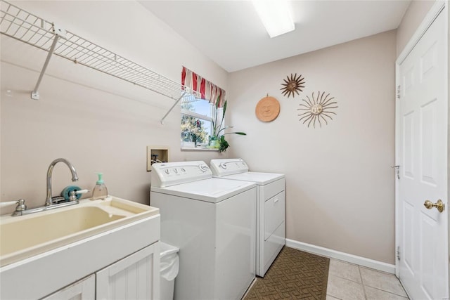 laundry room with baseboards, light tile patterned floors, laundry area, washer and dryer, and a sink