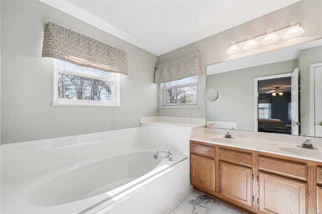 ensuite bathroom featuring a garden tub, plenty of natural light, and a sink