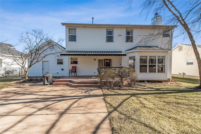 back of house with a deck, a yard, fence, and a chimney