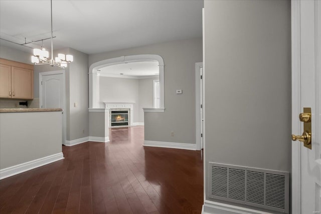 unfurnished living room with visible vents, dark wood-type flooring, a high end fireplace, and baseboards