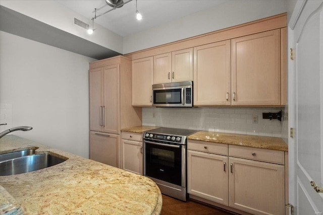 kitchen with stainless steel appliances, a sink, visible vents, backsplash, and light brown cabinetry