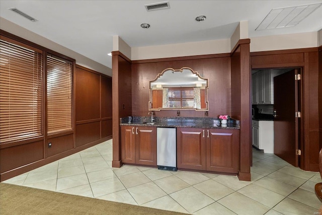 kitchen featuring dark stone countertops, visible vents, a sink, and light tile patterned flooring